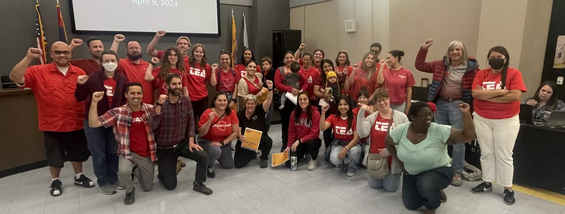 Group of educators wearing red shirts and holding up their fists