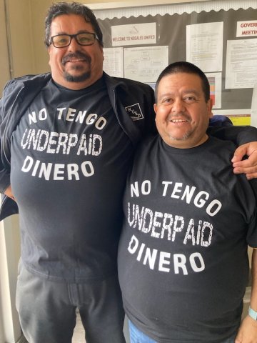 Two men wearing T-shirts that say "Underpaid - No Tengo Dinero"