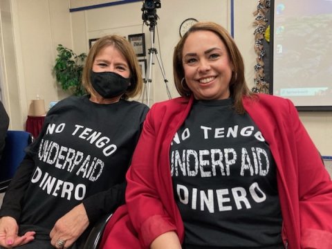 Two women wearing T-shirts that say "Underpaid - No Tengo Dinero"